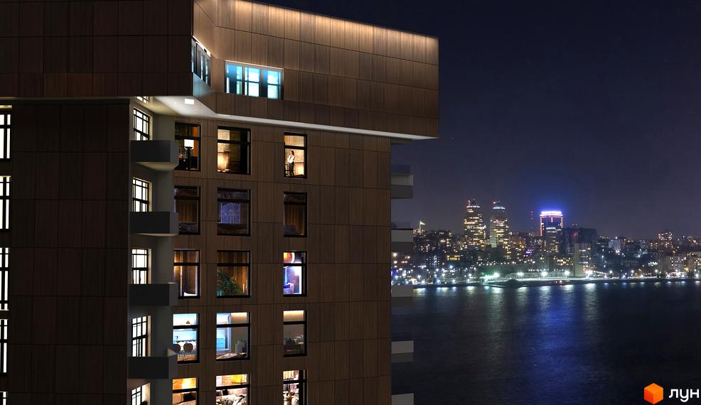Нічний вигляд Новобудови Grand Tower з темним фасадом та освітленими вікнами. На задньому плані видно нічне місто та водну гладь з відблисками вогнів.