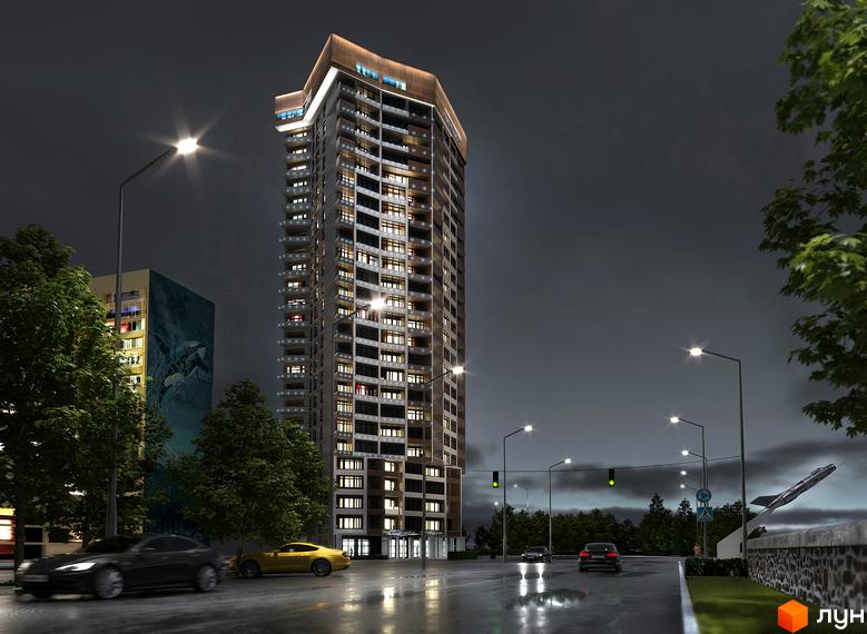 Висотна будівля Житлового комплексу Grand Tower вночі з підсвіченими вікнами та балконами. Поруч дорога з автомобілями та вуличними ліхтарями.