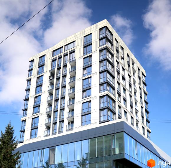 Зовнішній вигляд новобудови ЖК SOURENGE з білими фасадами, великими вікнами та балконами на тлі блакитного неба з хмарами. Будівельний проєкт розташований у місті.