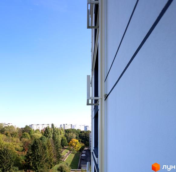 Зовнішній вигляд Новобудови SOURENGE з вікнами та балконами. Навколо дерева та зелені зони.