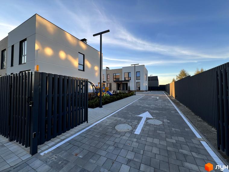 Таунхауси Soul City: світлі будинки з темними вікнами, брукована дорога з розміткою та темна огорожа.