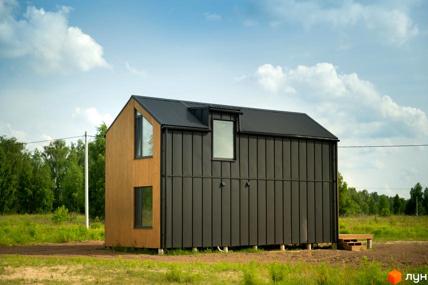 Котеджне містечко КМ Залісся Village: двоповерховий будинок з дерев'яною та чорною обшивкою, вікнами та прибудинковою територією з травою.