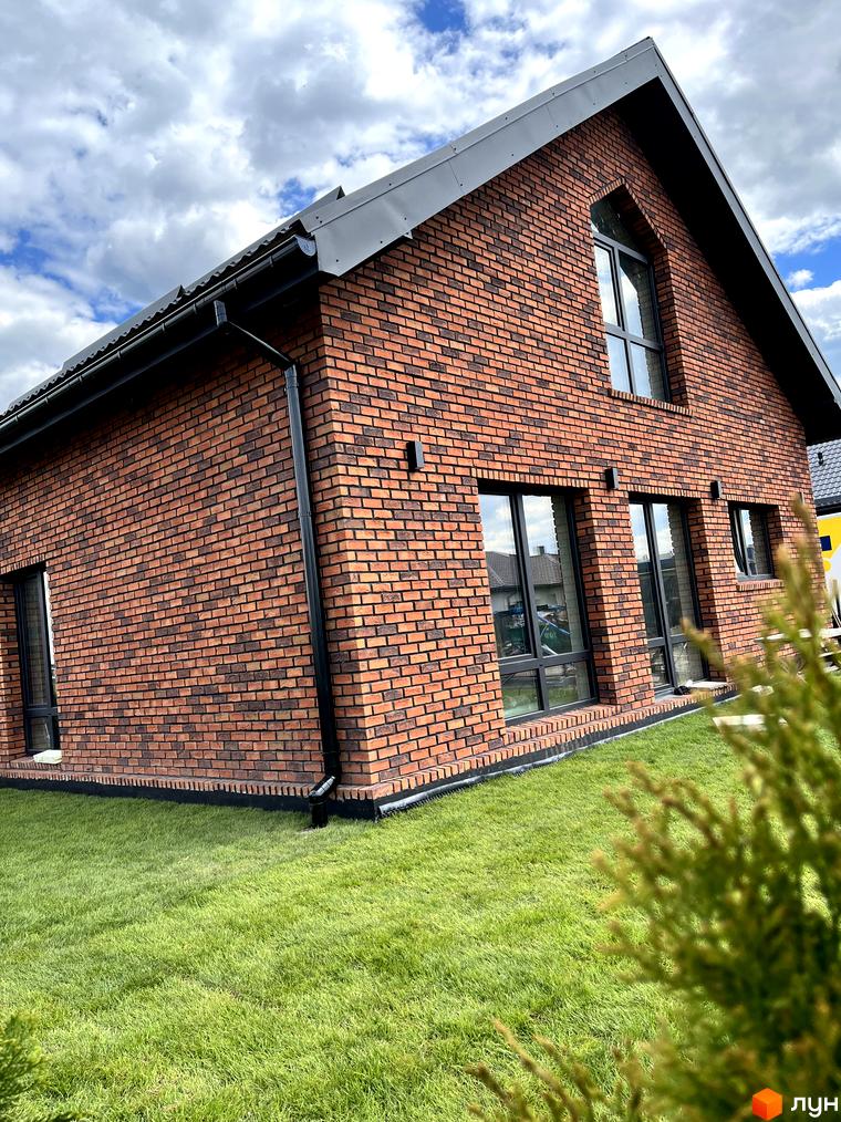 Зображення будинку в Котеджному містечку Одноповерховий Київ - Зубра. Навколо будинку зелений газон.