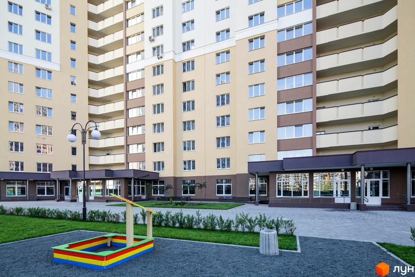 Зовнішній вигляд багатоповерхового будинку в Житловому районі Лісовий квартал. На передньому плані дитячий майданчик та прибудинкова територія.