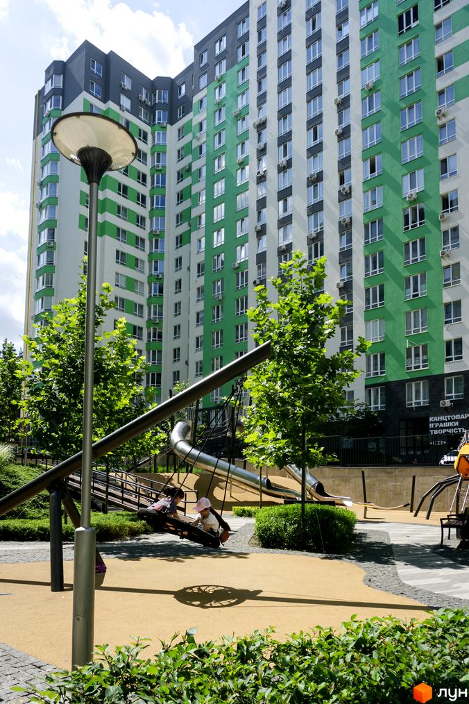 Житловий комплекс City Park з яскравим зеленим фасадом. На прибудинковій території дитячий майданчик зі спусками та гойдалками.