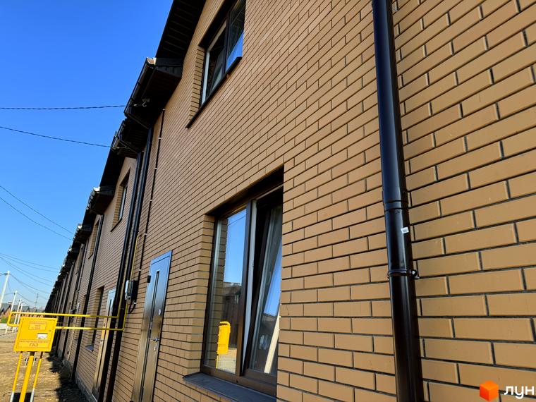 Котеджне містечко Весняний: ряд будинків зі світло-коричневої цегли, темними дахами та водостічними системами. Видно газові комунікації.