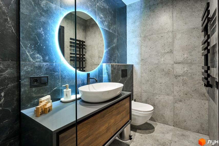 Інтер'єр ванної кімнати в FOMICH RESIDENCE GUESTHOUSES з круглим дзеркалом та білою раковиною. Плитка на стінах і підлозі сірого кольору.