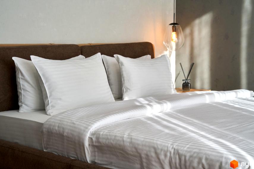 Фото спальні в FOMICH RESIDENCE GUESTHOUSES. Ліжко з білою постільною білизною та подушками, коричневе узголів'я.