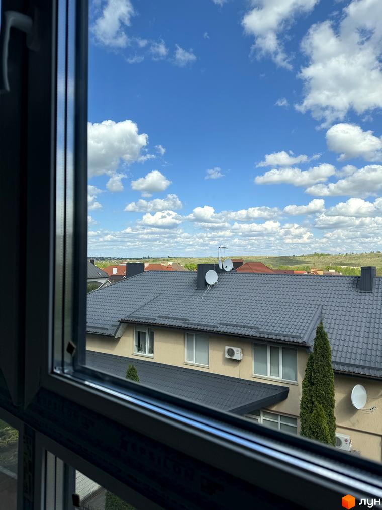 Будівельний проєкт Буковинська 20А. Вид з вікна на дахи будинків та блакитне небо з хмарами.