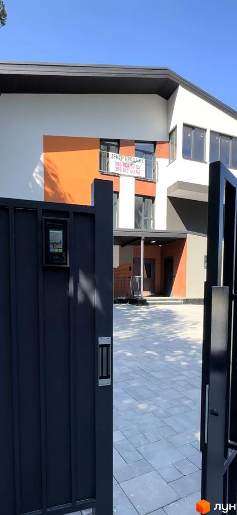 Житловий комплекс Буковинська 20А з оранжевими та білими фасадами, огороджена територія з домофоном та бруківкою.