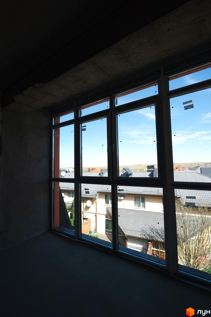 Вид з вікна на житловий комплекс Буковинська 20А з сірими дахами та супутниками на дахах будинків.