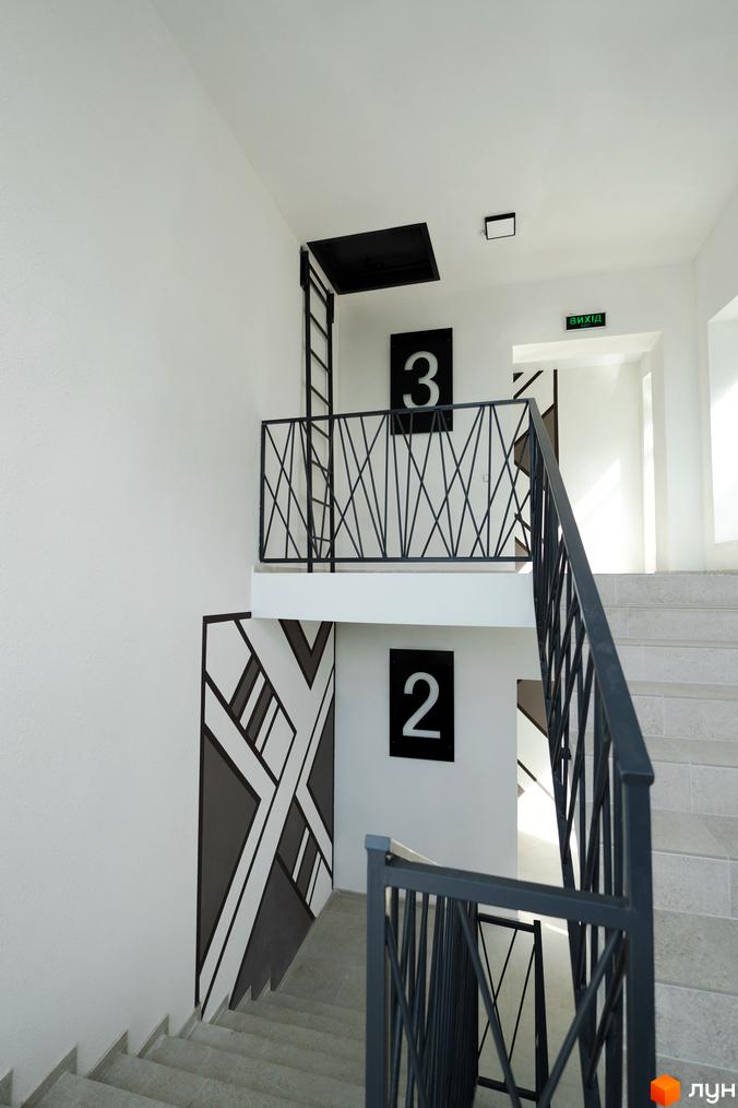 Сходи в житловому комплексі Буковинська 20А з номерами поверхів 2 та 3. Сучасний дизайн сходової клітки з чорними перилами та геометричним візерунком на стіні.