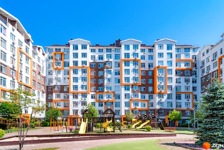 Житловий комплекс Orange Park: фасади будівель з помаранчевими елементами та дитячий майданчик з гірками та гойдалками.