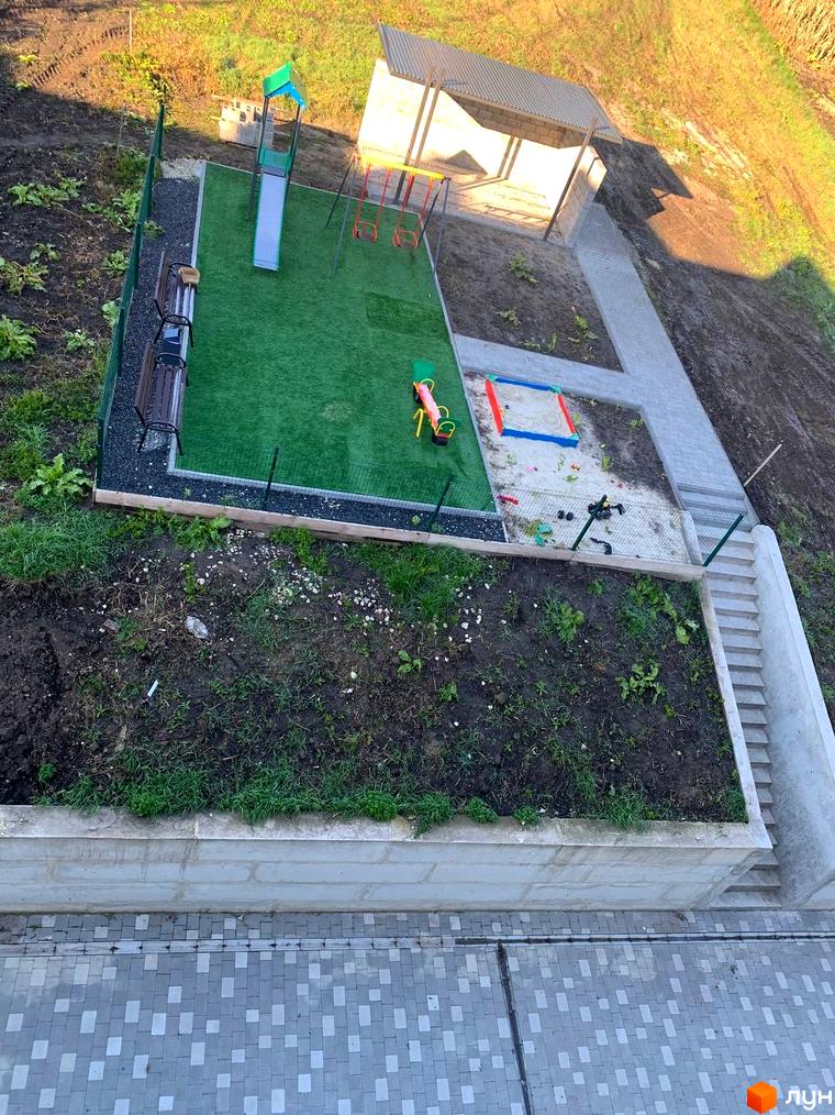 Дитячий майданчик у дворі ЖК ПАНОРАМА з гіркою, гойдалками, пісочницею та лавками для відпочинку. Поруч розташований навіс та сходи.