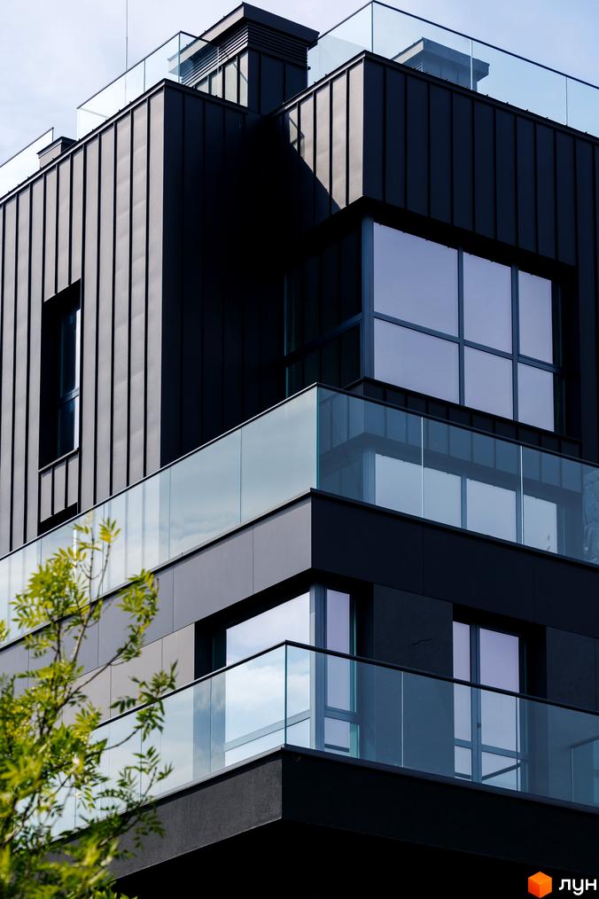 Фасад житлового комплексу Avalon Prime з темними панелями та скляними балконами. Сучасна архітектура новобудови з великими вікнами.