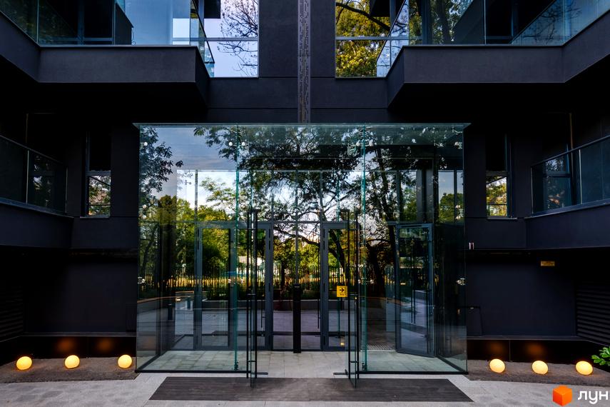 Житловий комплекс Avalon Prime з сучасною скляною вхідною групою та охайною прибудинковою територією з освітленням.