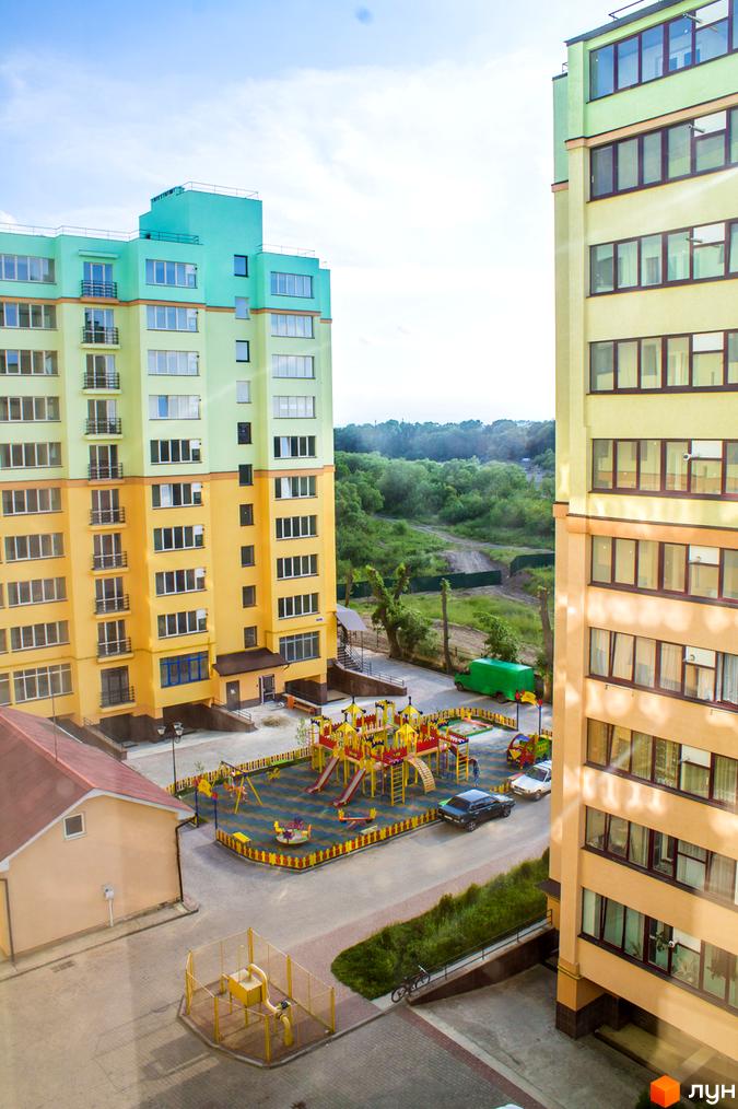 Зображення житлового комплексу Веселка річкова з яскравими фасадами та дитячим майданчиком. Вигляд з вікна на територію новобудови.