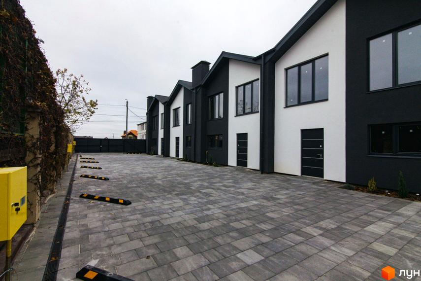 Вигляд фасаду та прибудинкової території Житлового комплексу на вул. Шалімова, 36. Двоповерхові будинки з чорно-білим оздобленням.