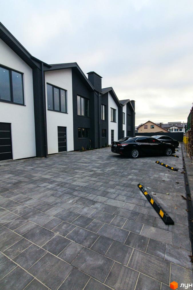 Зображення фасаду та прибудинкової території Житлового комплексу на вулиці Шалімова, 36. На передньому плані припарковані автомобілі.