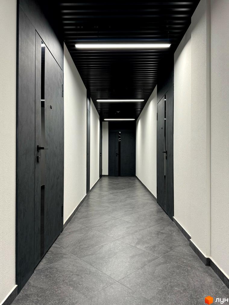 Сучасний коридор у новобудові ЖК GREENHOUSE CITY з темними дверима та світлими стінами. Підлогове покриття виконане з сірої плитки.