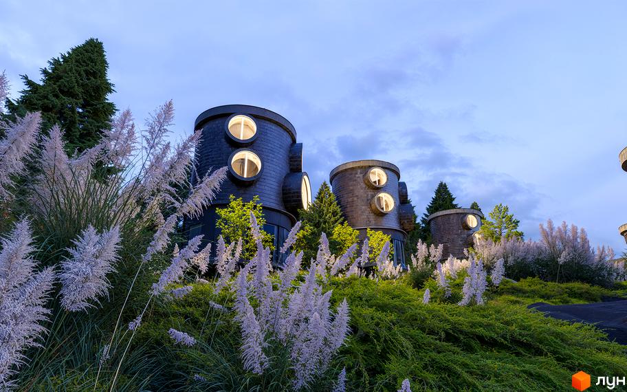 Зовнішній вигляд Котеджного містечка Малахіт з циліндричними будинками та круглими вікнами. Навколо зелені насадження та декоративні трави.