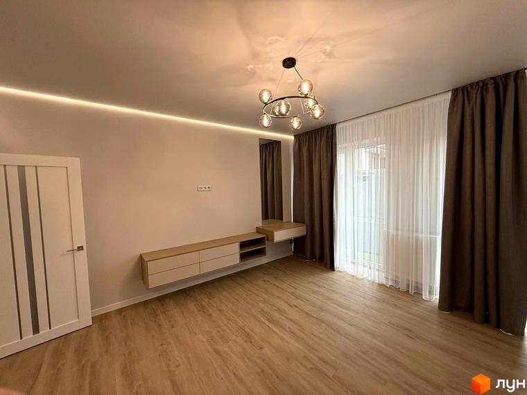 Вітальня в новобудові ЖК Comfort City з білими дверима, підвісною тумбою та коричневими шторами. Інтер'єр оформлений у світлих тонах з дерев'яною підлогою.