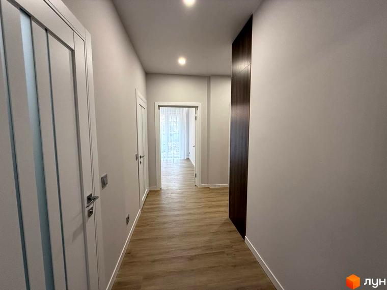 Комплекс Comfort City. Сучасний коридор з дверима та дерев'яною підлогою, що веде до світлої кімнати з вікнами.