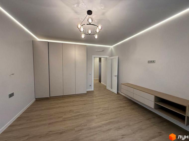 Житловий комплекс Comfort City. Простора кімната з вбудованими шафами та телевізійною тумбою.