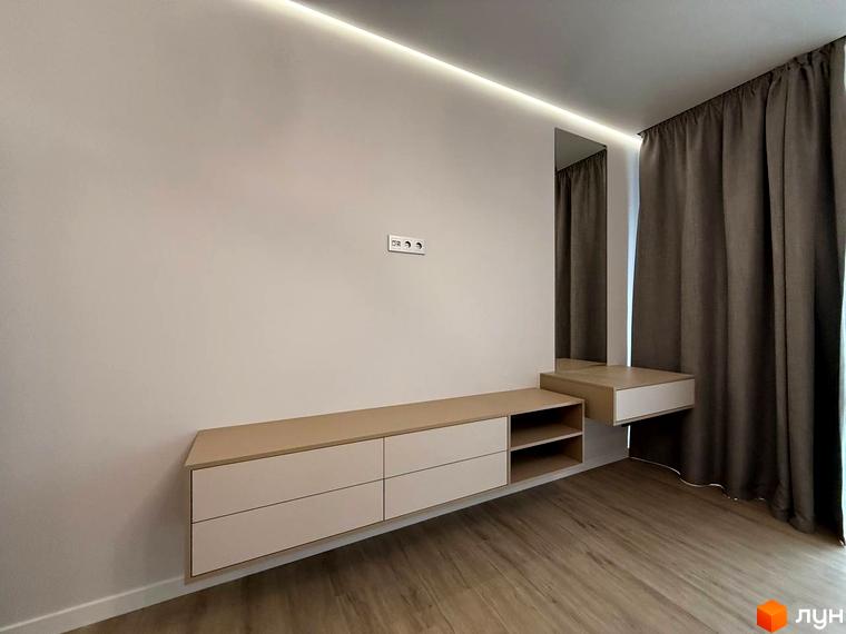 Інтер'єр кімнати з підвісною тумбою під телевізор та дзеркалом у ЖК Comfort City. Сірі штори доповнюють мінімалістичний дизайн.