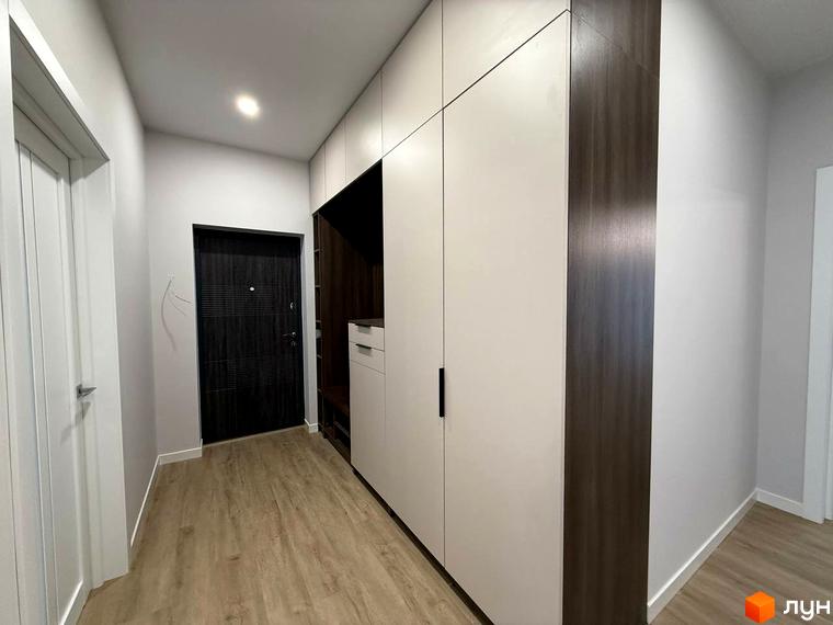Передпокій у новобудові ЖК Comfort City з темними дверима та великою шафою. Підлога покрита світлим ламінатом.
