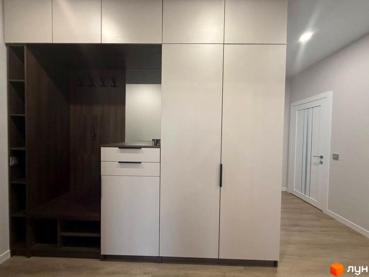Передпокій з вбудованими шафами та вішаками для одягу в ЖК Comfort City. Білі двері з вертикальними скляними вставками ведуть до квартири.