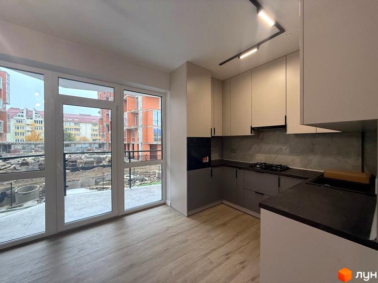 Кухня в житловому комплексі Comfort City з великими вікнами, що виходять на будівельний майданчик та сусідні будинки.