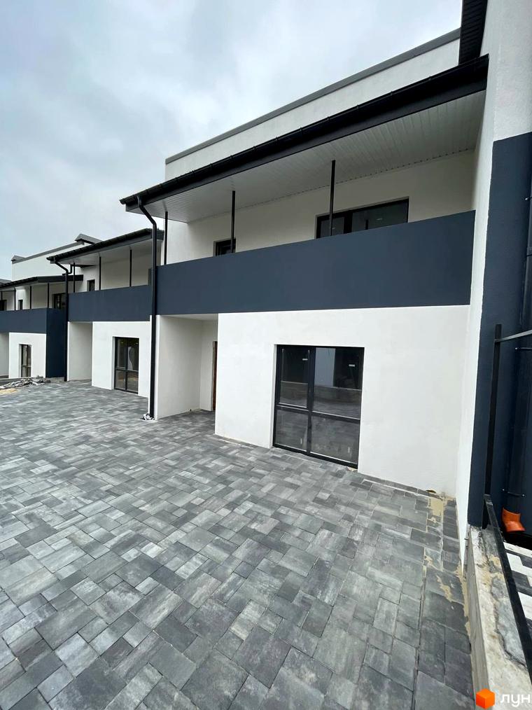 Зовнішній вигляд таунхаусів на Молодіжній з сірим патіо. Комплекс має білі фасади з темними елементами та балконами.