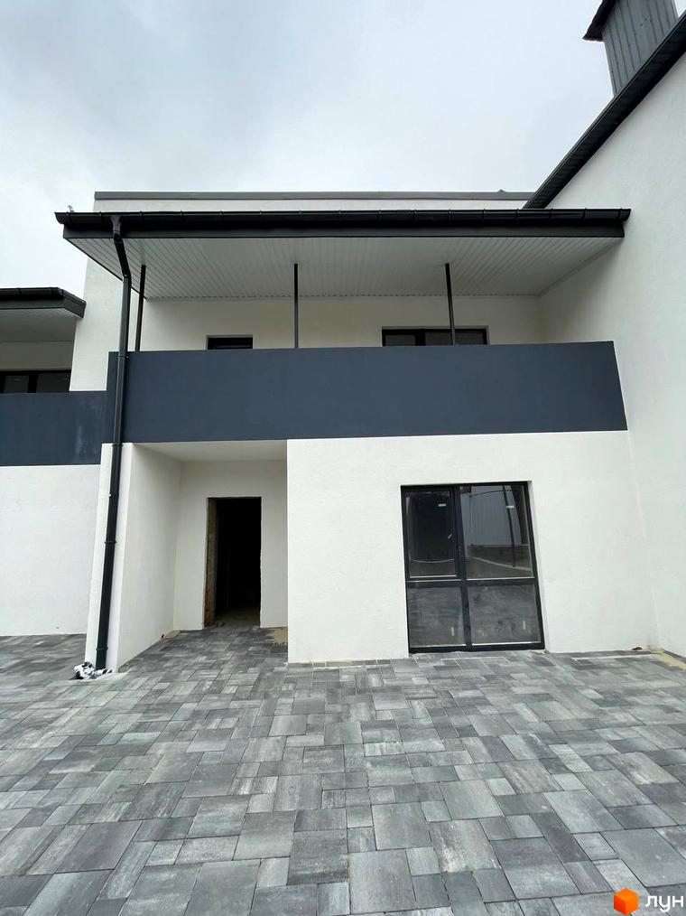 Зовнішній вигляд таунхаусів на Молодіжній з сірим фасадом та білими стінами, з панорамними вікнами та бруківкою на прибудинковій території.