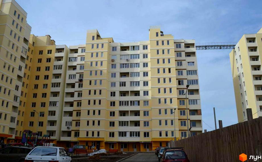 Житловий комплекс Суворівський 2 з жовтими багатоповерховими будинками. На прибудинковій території є парковка для автомобілів.