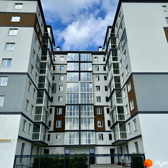 Зовнішній вигляд новобудови ЖК Idilika Avenue з панорамним склінням та балконами. Навколо будинку облаштована прибудинкова територія з огорожею та зеленню.