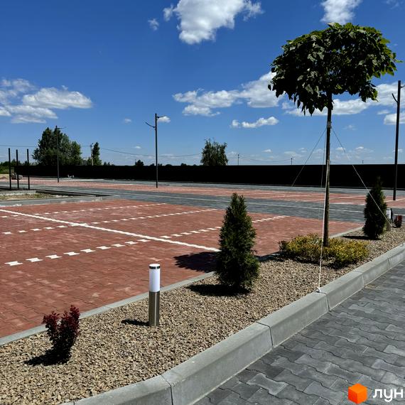 Новобудова Idilika Avenue з червоною бруківкою та зеленими насадженнями. Територія комплексу облаштована ліхтарями та деревами.