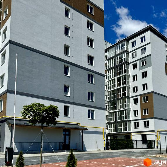 Житловий комплекс Idilika Avenue - це сучасна новобудова з сірими та білими фасадами, вікнами з панорамним склінням та зеленою прибудинковою територією.