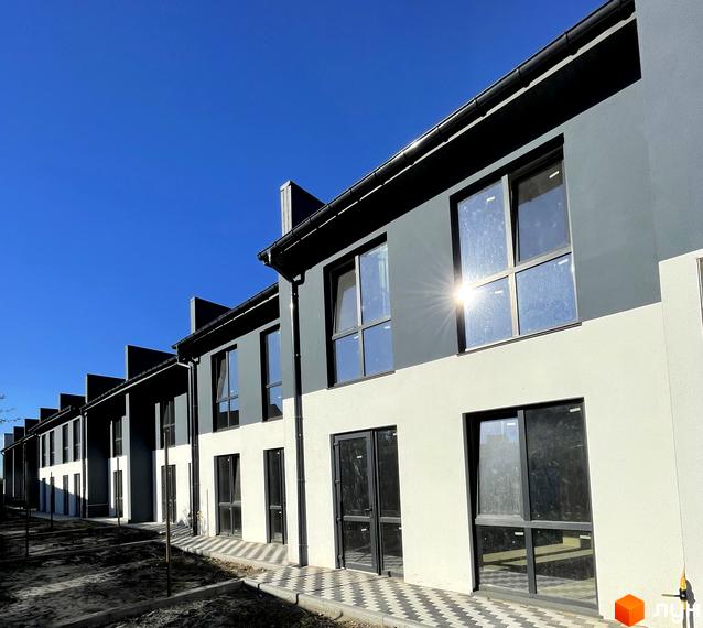 Ряд таунхаусів Belissimo з двоколірними фасадами та великими вікнами. Перед будинками видно ділянку з ґрунтом та вимощену доріжку.