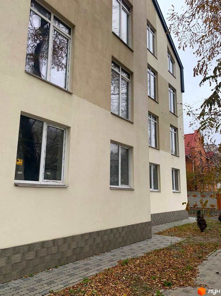 Клубний будинок „На Макіївській“ з біло-бежевим фасадом та сірою цокольною плиткою. Поруч доріжка з бруківки та опале листя.