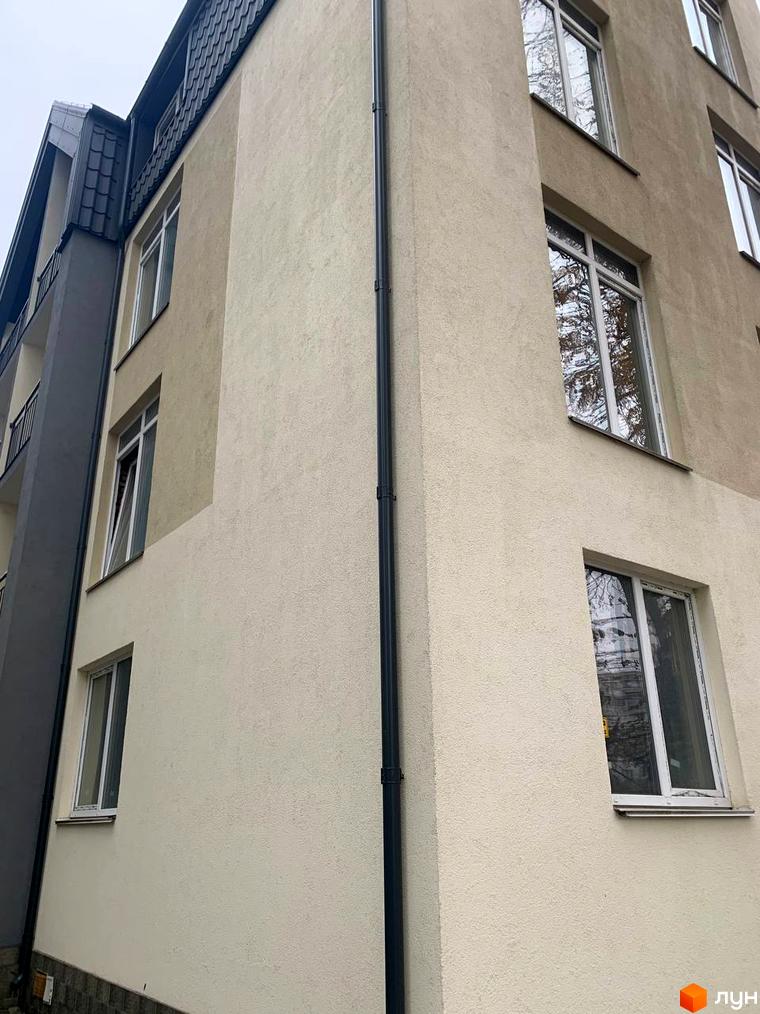 Зовнішній вигляд клубного будинку „На Макіївській“ з світлою штукатуркою та вікнами. Фасад будівлі має кілька поверхів та дах з темної черепиці.