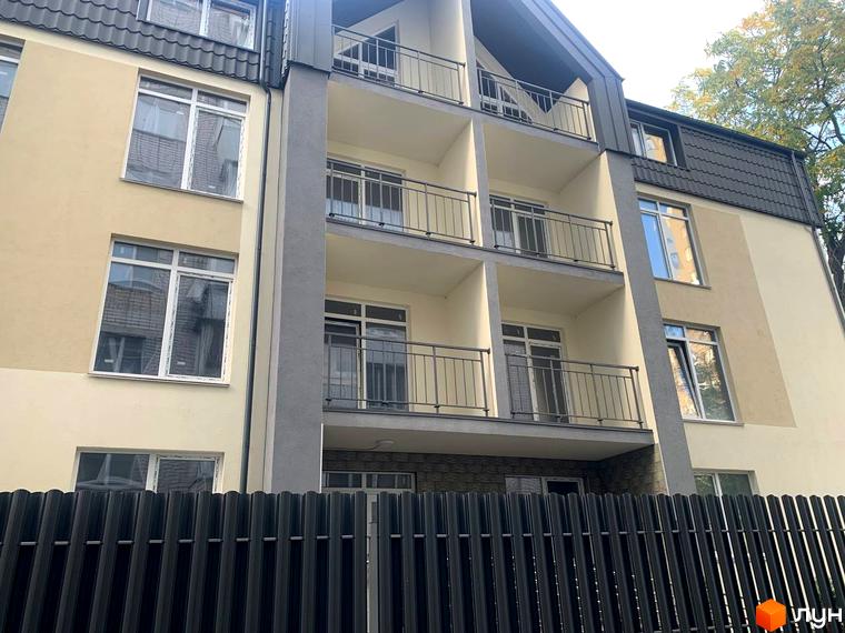 Клубний будинок „На Макіївській“: фасад будівлі з балконами та вікнами, огороджений парканом. Зовнішній вигляд новобудови.