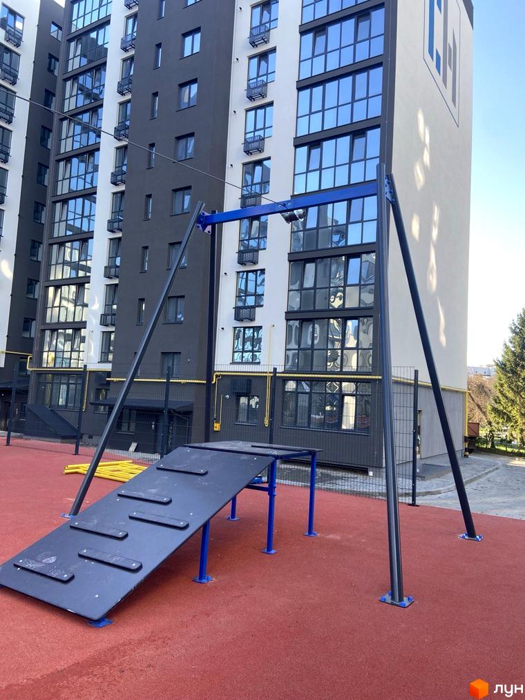 Житловий комплекс Comfort House з багатоповерховими будинками та зоною відпочинку на прибудинковій території. На фасаді будівлі присутні великі вікна та балкони.