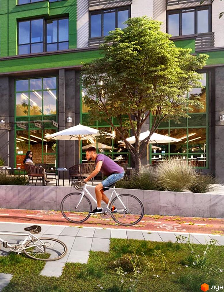Житловий комплекс LIKO-GRAD Perfect Town. Чоловік їде на велосипеді повз будівлю з великими вікнами та деревами. Біля будинку є зона відпочинку з парасольками.