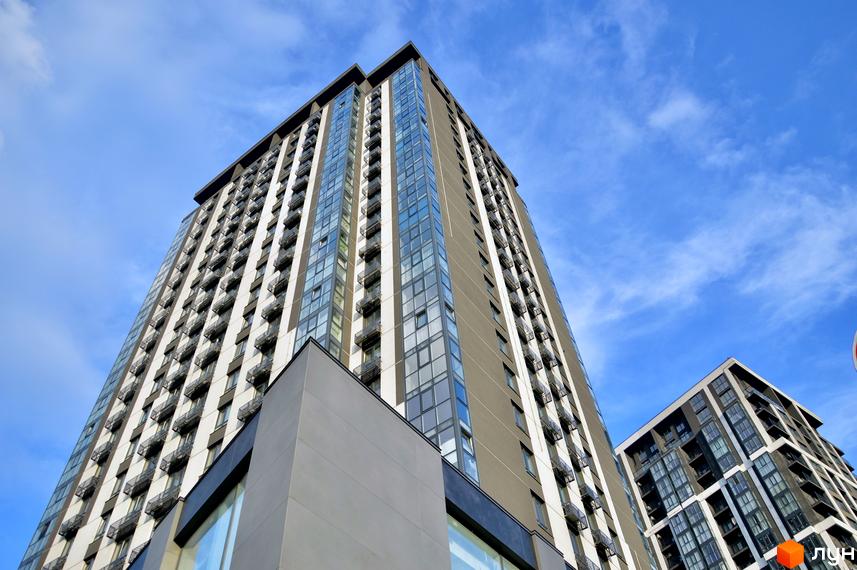 Фасад новобудови ЖК Avalon Up з численними балконами та панорамними вікнами на тлі блакитного неба. Сучасна архітектура житлового комплексу.