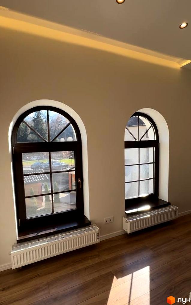 Житловий комплекс Shayan lux house з арочними вікнами та радіаторами опалення. Зовні видно дерева та автомобілі.