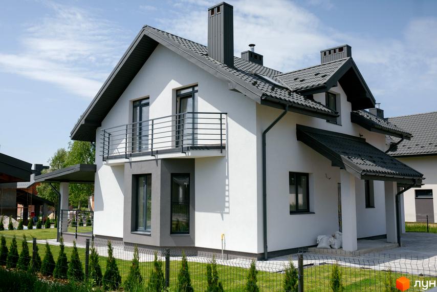 Котеджне містечко Praud Hills: білий двоповерховий будинок з сірим дахом та балконом. Озеленена прибудинкова територія з парканом та молодими деревами.