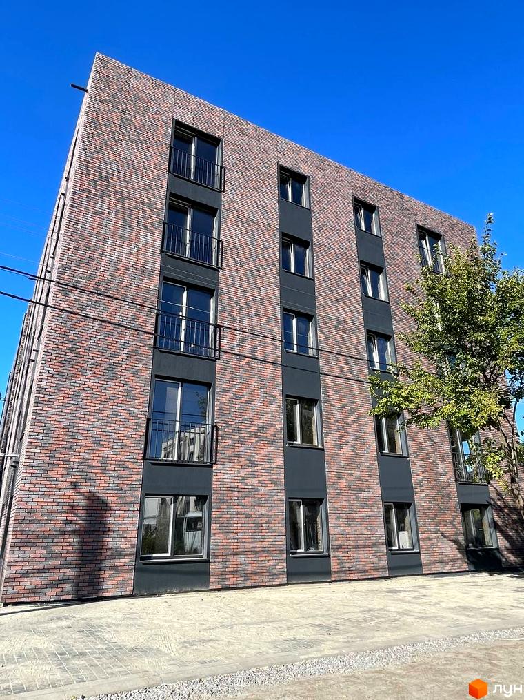 Новобудова Інститутська: багатоквартирний будинок з фасадом з червоної та сірої цегли, вікнами та балконами. Прибудинкова територія з бруківкою.