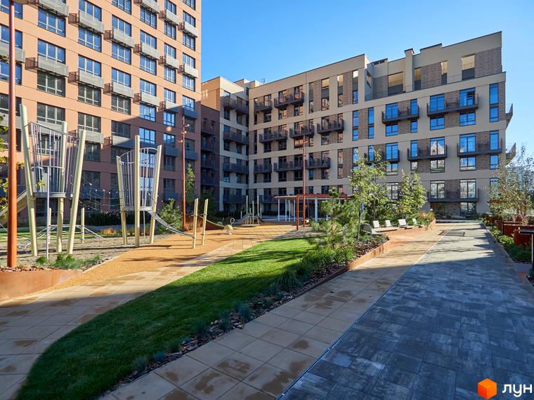 Багатоповерхові житлові будинки Будинок на Вавилових з вікнами та балконами. На прибудинковій території дитячий майданчик, газони та доріжки.