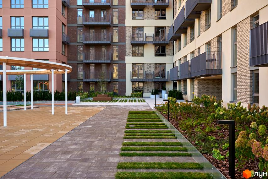 Будинок на Вавилових має фасади з цегли та світлих панелей, балкони. Прибудинкова територія з доріжками, зеленими насадженнями та альтанкою.